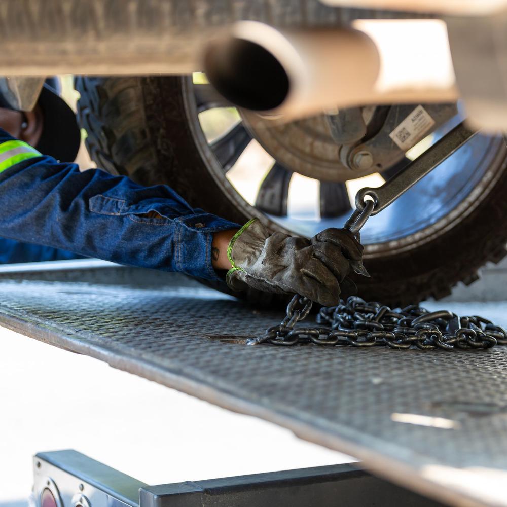 Tow operator chaining a pickup wheel down on a flatbed