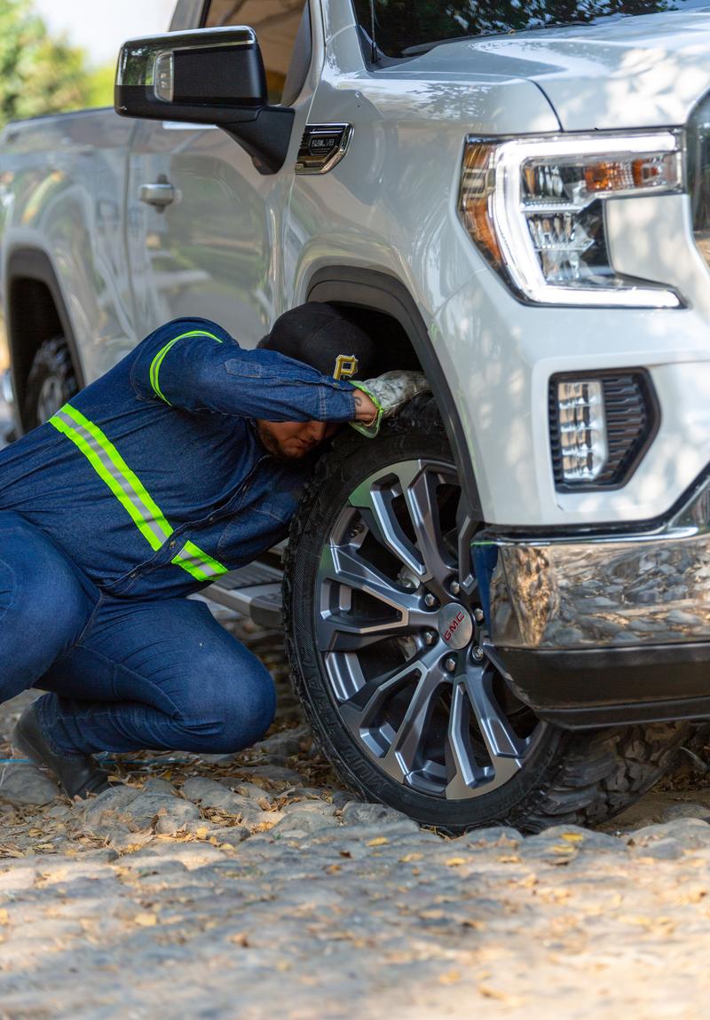 Tow truck operator checking the front wheel of a pickup